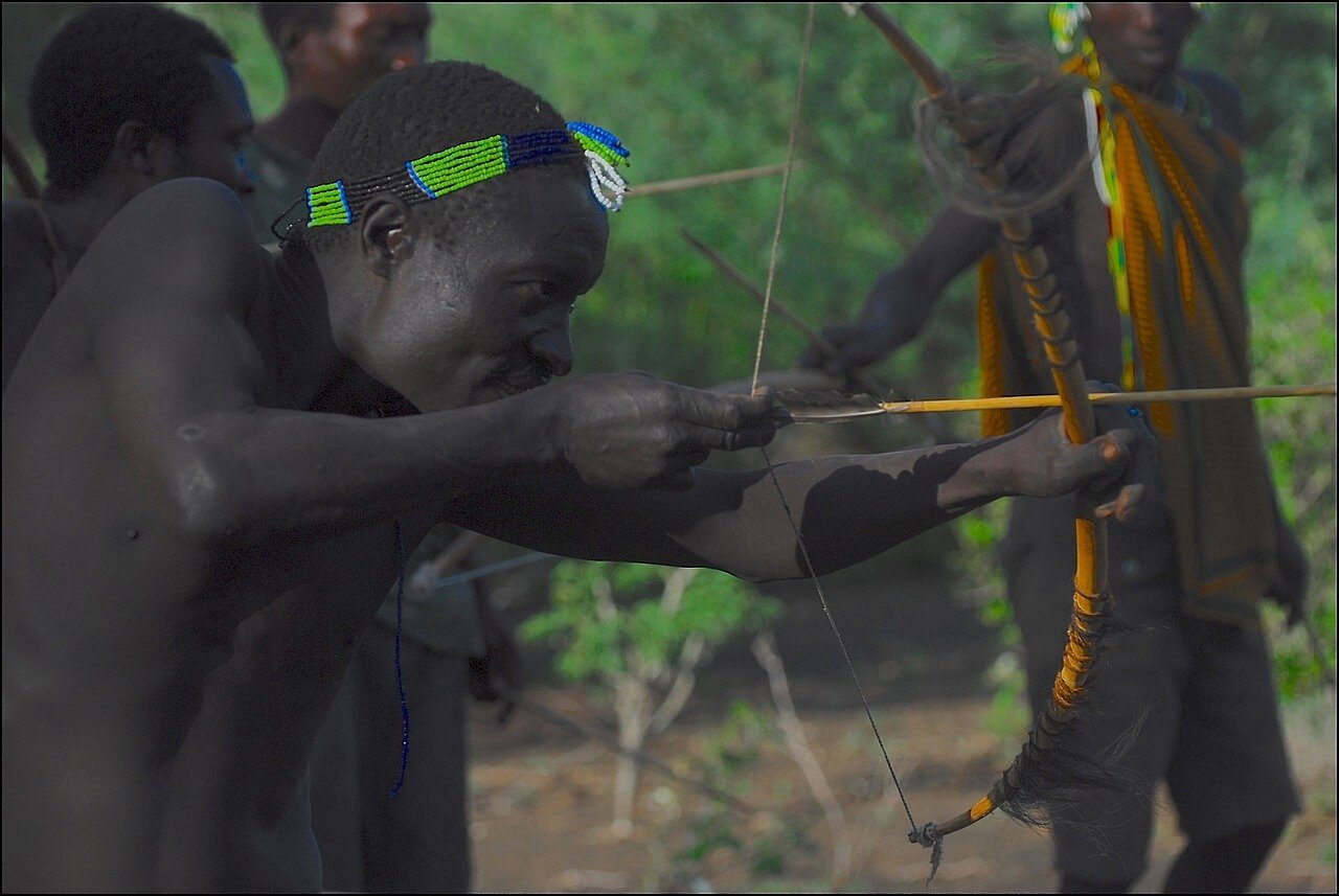 Hadzabe hunters drawing traditional bows