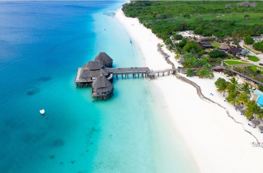 Aerial view of a wooden jetty over turquoise water on a white-sand Zanzibar beach